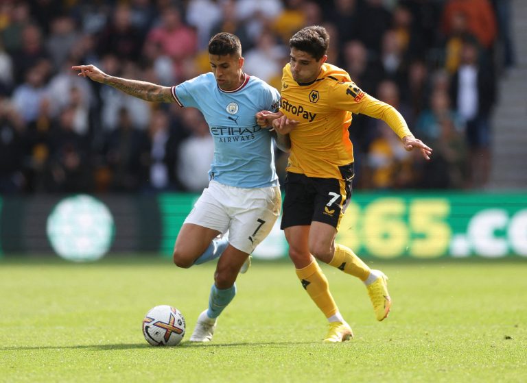Man City's Joao Cancelo is challenged by Pedro Neto