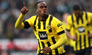 Soccer player in yellow jersey points to sky.