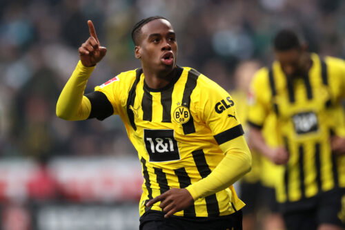 Soccer player in yellow jersey points to sky.