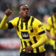 Soccer player in yellow jersey points to sky.