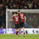 Two soccer players in striped jerseys embrace.