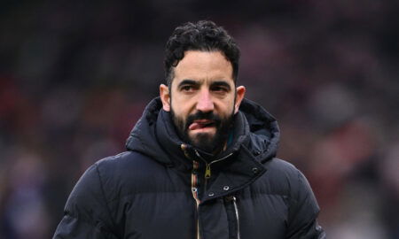 Man with black hair in coat bites tongue.