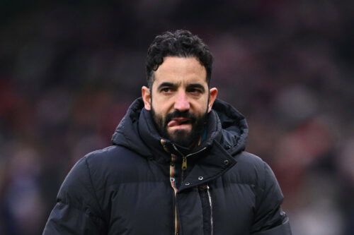 Man with black hair in coat bites tongue.