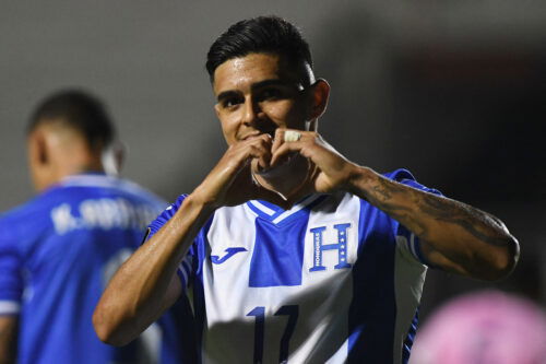 Player signals heart with hands after scoring goal.