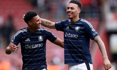 Soccer players in navy jerseys embrace.