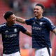 Soccer players in navy jerseys embrace.