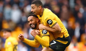 Two soccer players in orange jerseys hug.