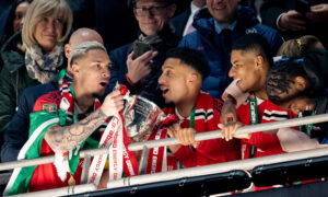 Soccer players lift trophy.