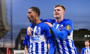 Soccer players in blue and white striped jerseys celebrate goal together.