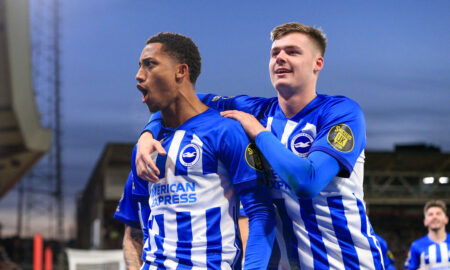 Soccer players in blue and white striped jerseys celebrate goal together.
