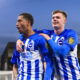 Soccer players in blue and white striped jerseys celebrate goal together.