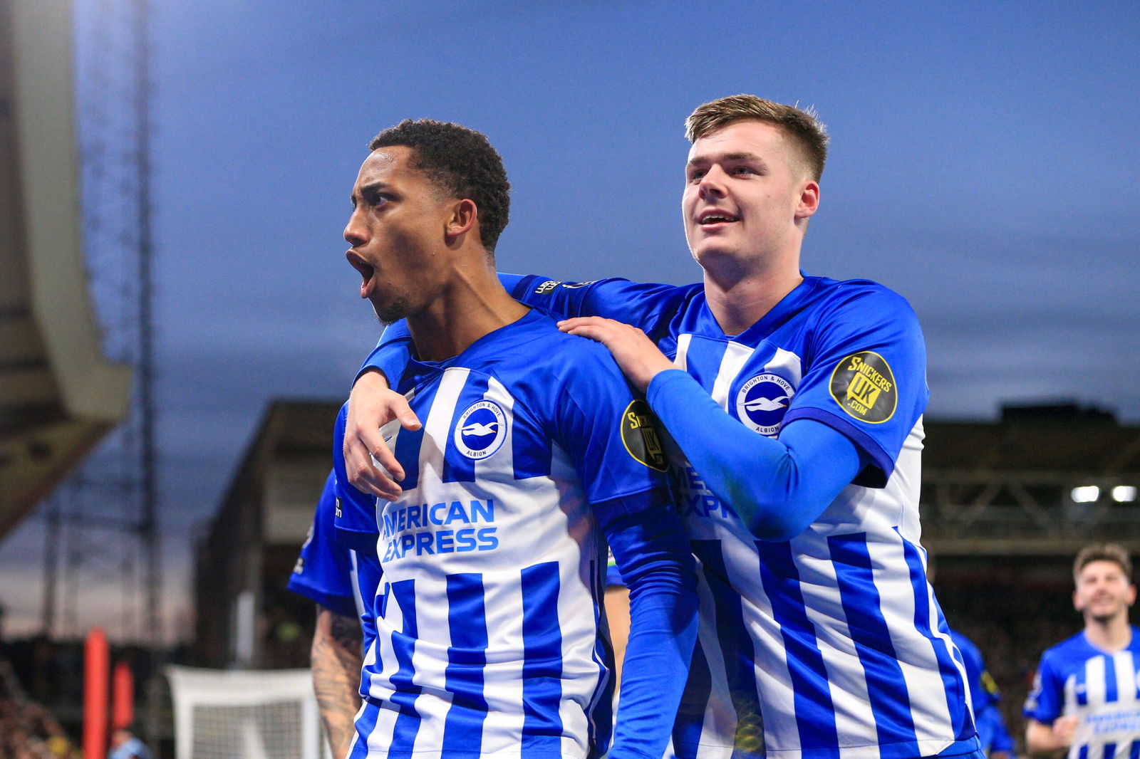 Soccer players in blue and white striped jerseys celebrate goal together.