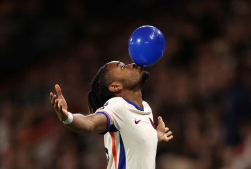 Voetballer met blauwe ballon in zijn mond.