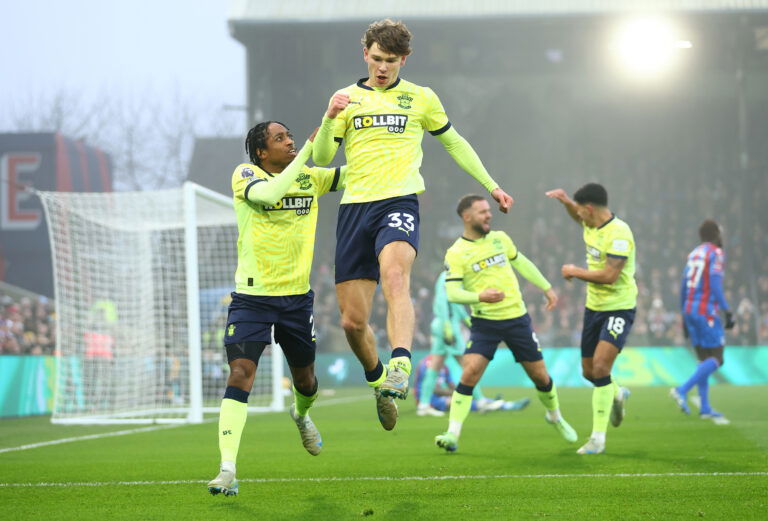 Soccer players in fluorescent yellow jerseys celebrate goal in rain.