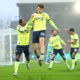 Soccer players in fluorescent yellow jerseys celebrate goal in rain.