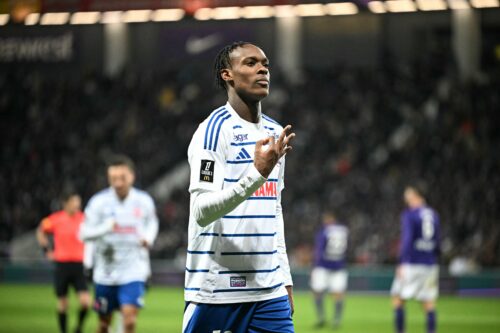 Soccer player in white and blue striped jersey celebrates goal.