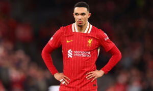 Soccer player in red hands on hips.