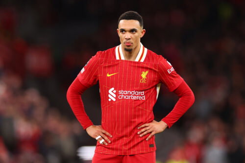 Soccer player in red hands on hips.