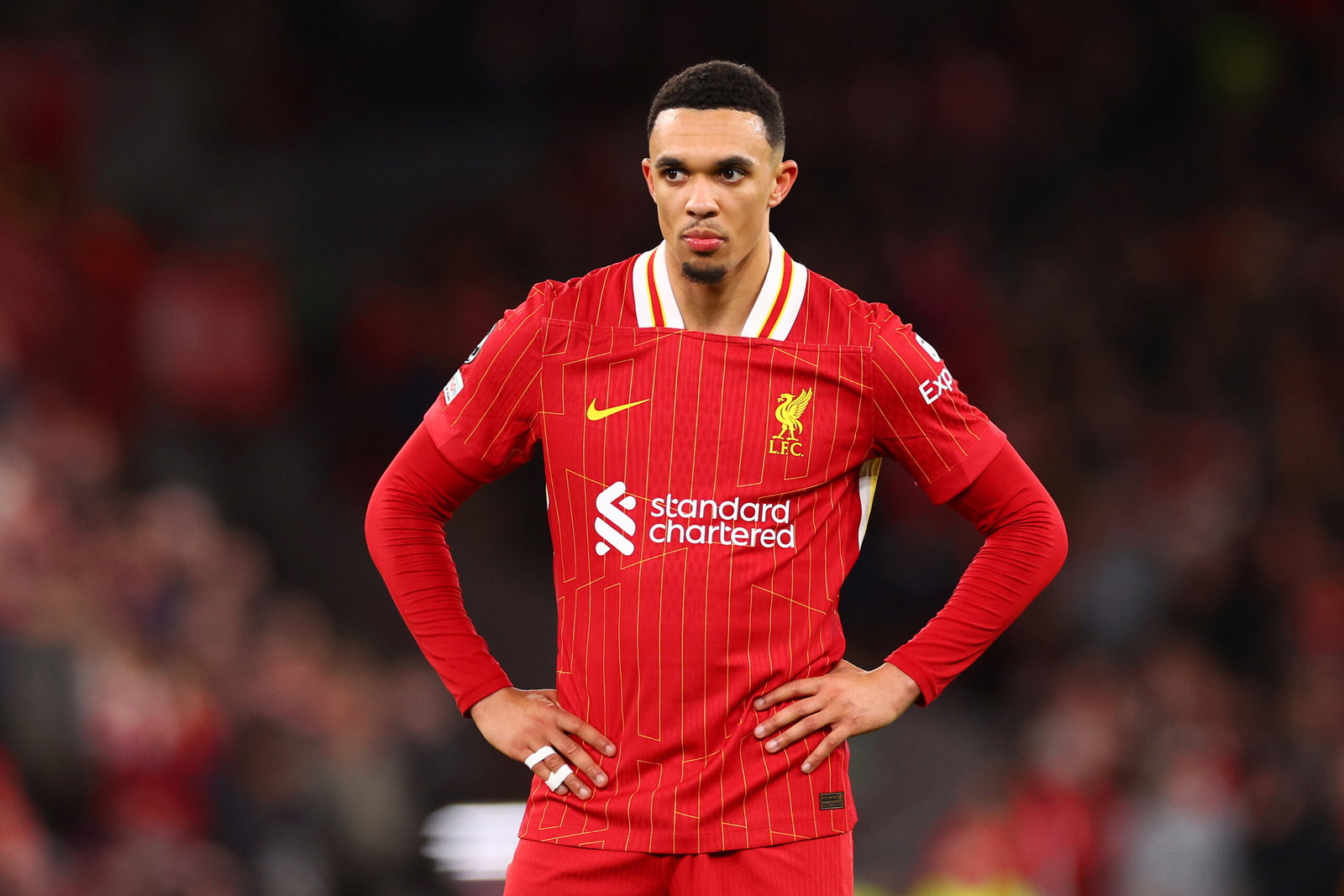Soccer player in red hands on hips.