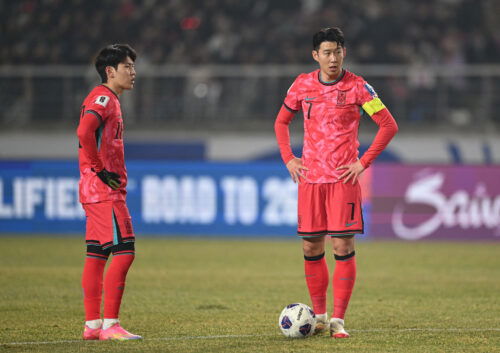 Soccer players in pink jerseys line up free kick.